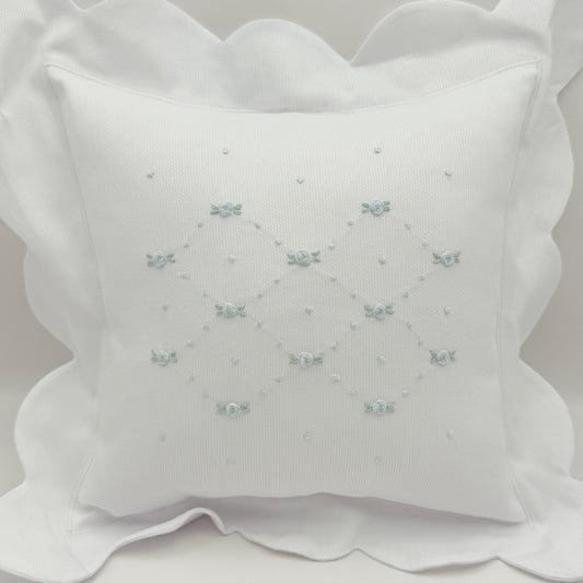 White decorative pillow with embroidered patterns on a light gray background
