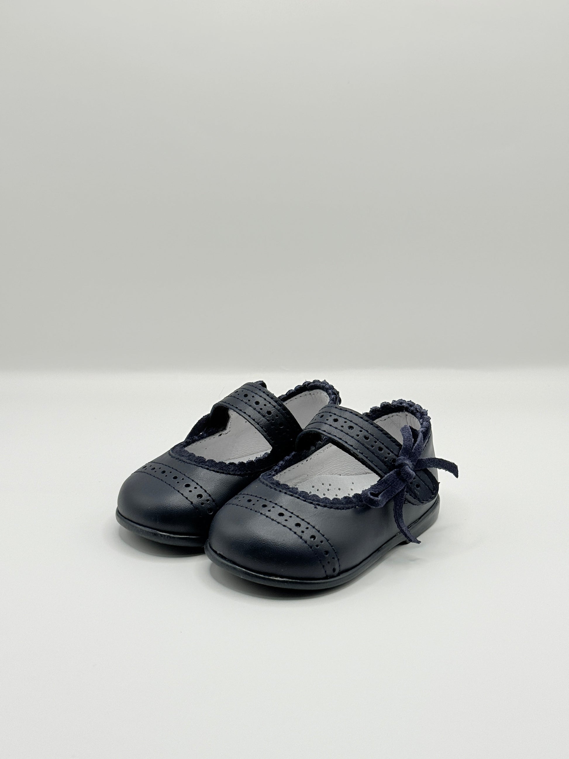Black leather shoes with criss-cross design on a light gray background