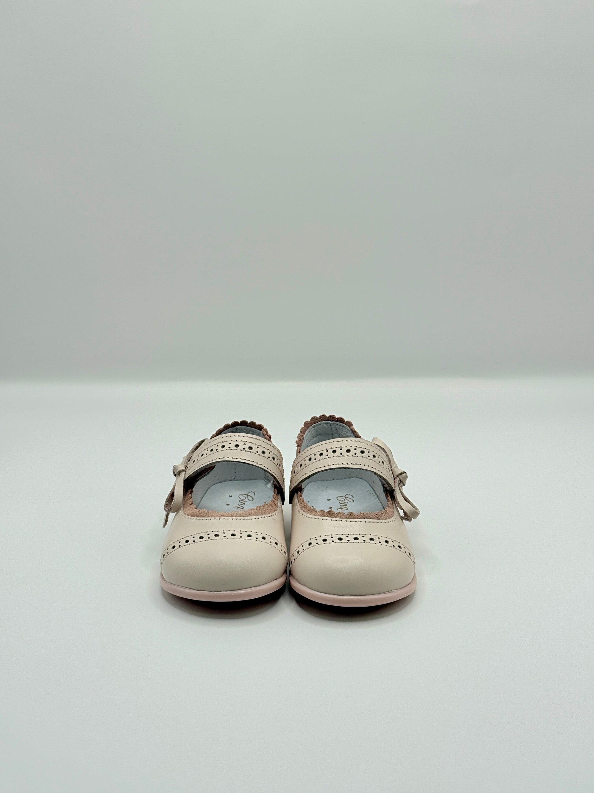 Pair of beige children's shoes on a light gray background